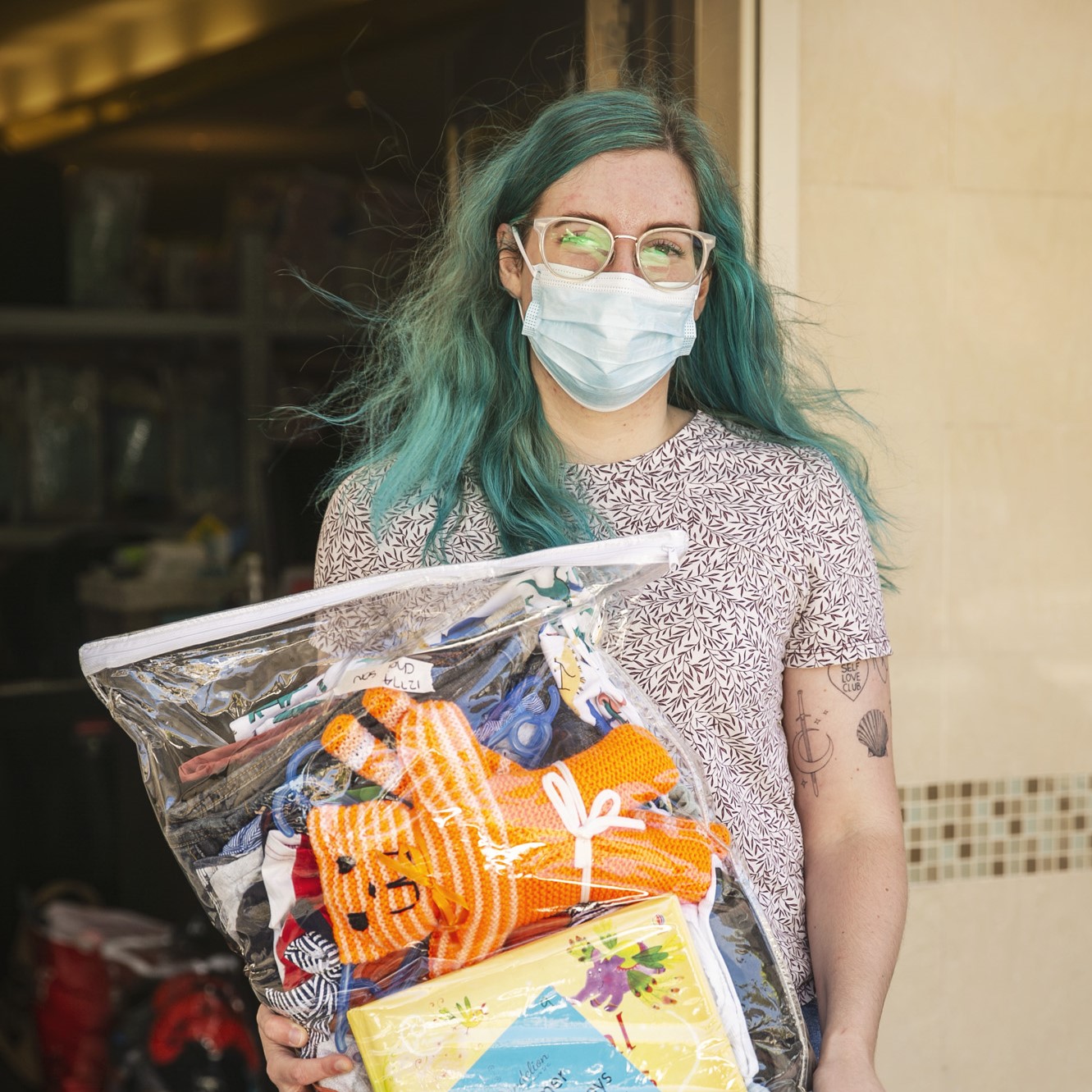 social worker with blue hair holding a toy pack